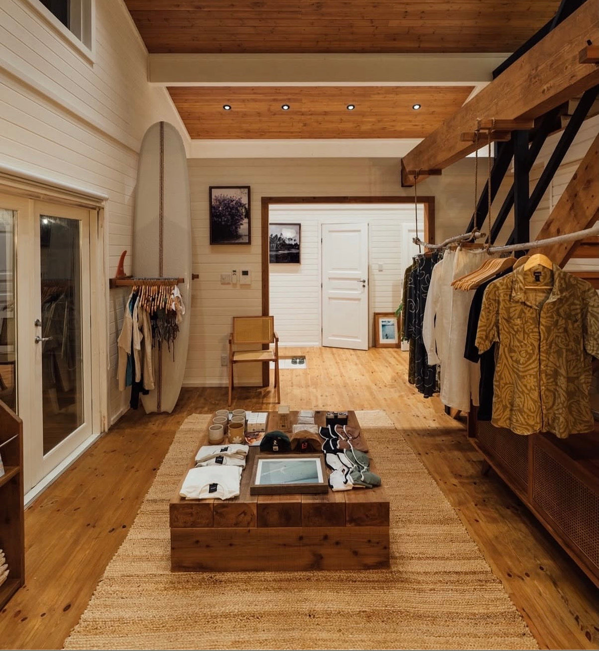 Saltwater Cowboy Board Butter™ surf shampoo and conditioner bars displayed in a boutique surf shop interior, featuring wood-paneled walls, a surfboard display, and apparel racks in Japan. Reef-safe surf care for wholesale surf shop retail.