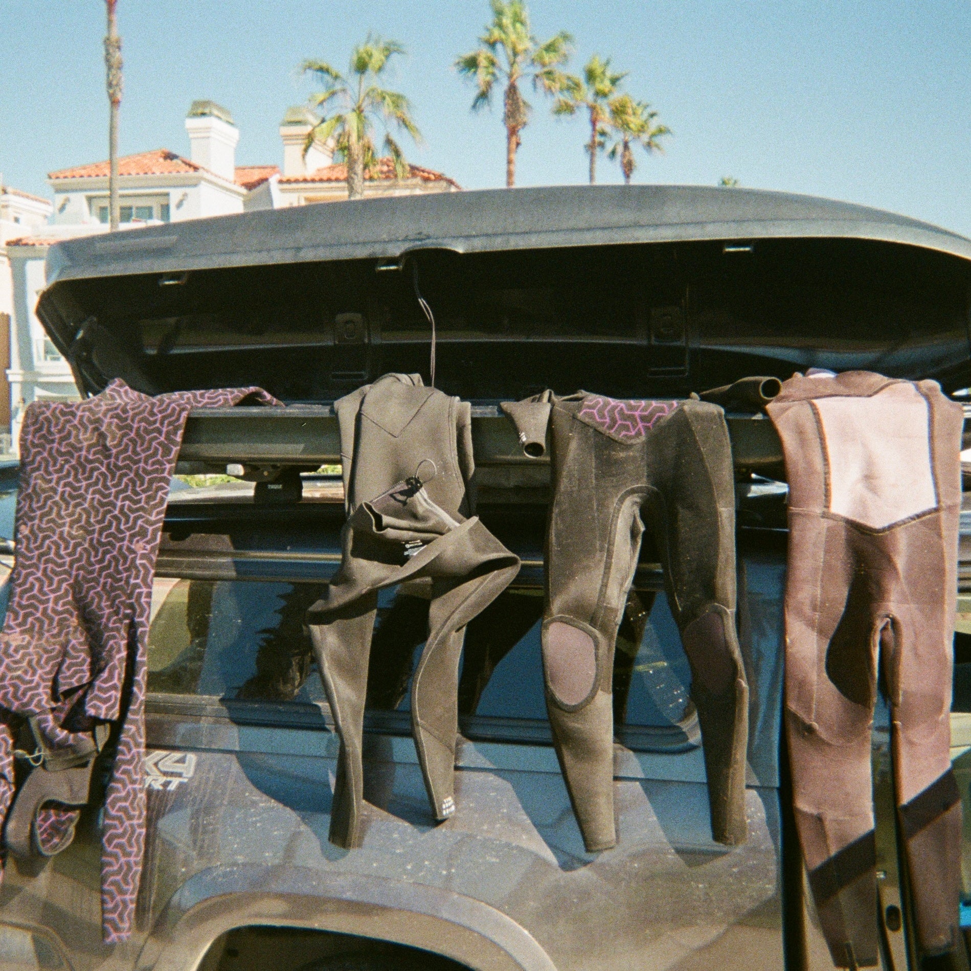 Wetsuits hanging from a car on a surf road trip with plastic free shampoo and conditioner.